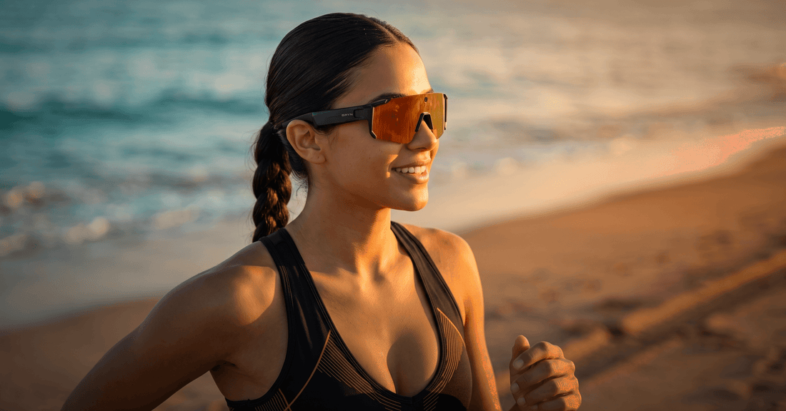 Woman running at the beach wearing smart glasses, exploring open-ear headphones for running and cycling.