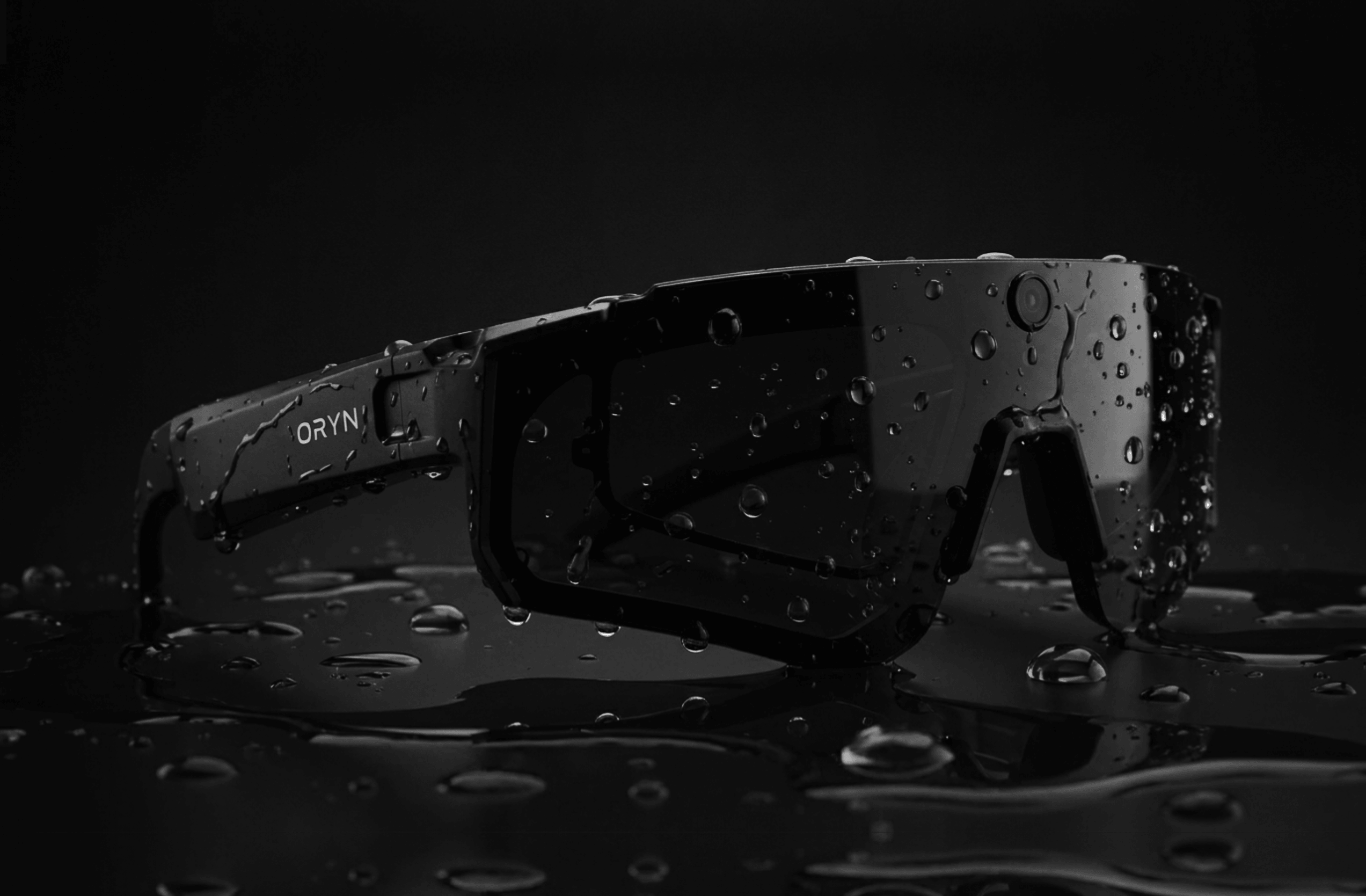 Black Oryn AI Sports Camera Glasses with water droplets on a dark background.